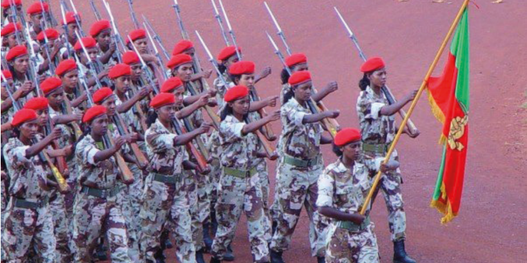 Joukko naissotilaita marssii maastopuvuissa ja aseet olalla. Etummainen kantaa Eritrean puna-vihreää lippua.