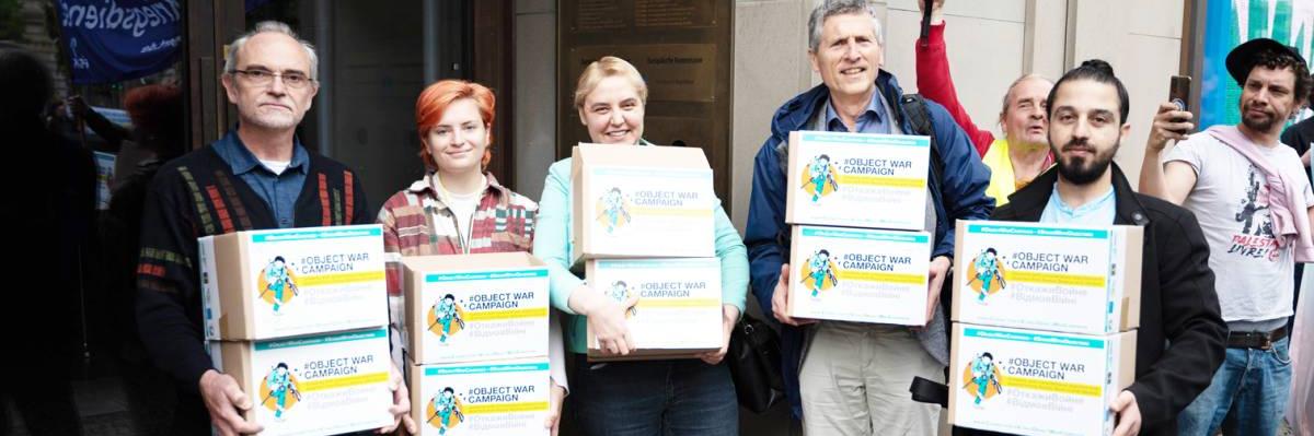 Activists holding the signatures collected for the #ObjectWarCampaign, in front of the European Commission in Berlin.