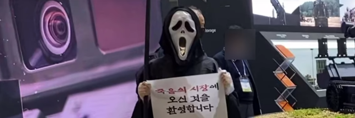 Viikatemieheksi pukeutunut mielenosoittaja pitää kylttiä täynnä koreankielistä tekstiä