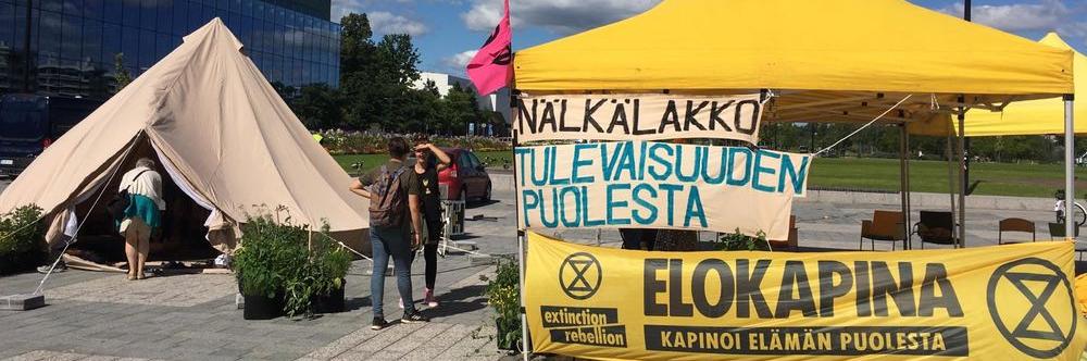 Helsingin kansalaistorille pystytetyssä keltaisessa teltassa on banderolleissa tekstit: "Nälkälakko tulevaisuuden puolesta" ja "Elokapina - Kapinoi elämän puolesta".