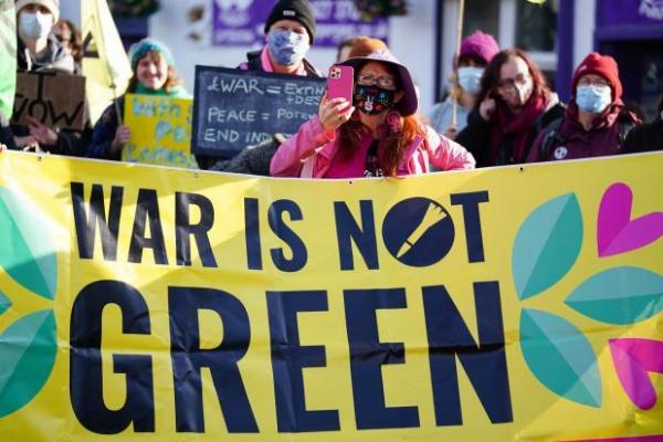 Mielenosoittaja "War is not green" -kyltin kanssa