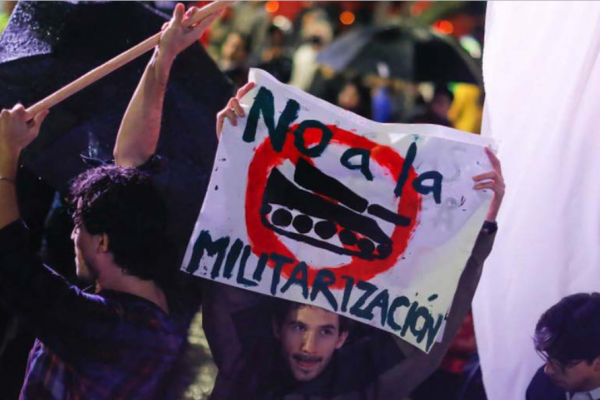 Meksikolainen mielenosoittaja pitää kädessään kylttiä: "No a la militarizacion!"