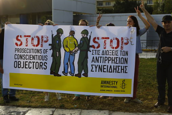 people standing with a banner that reads - stop prosecution of conscientious objectors